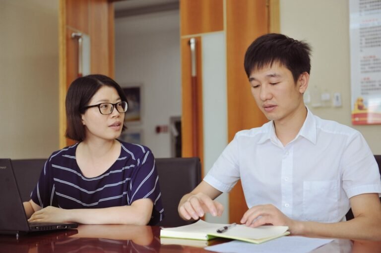 Two adult learners talking across a table during an English lesson